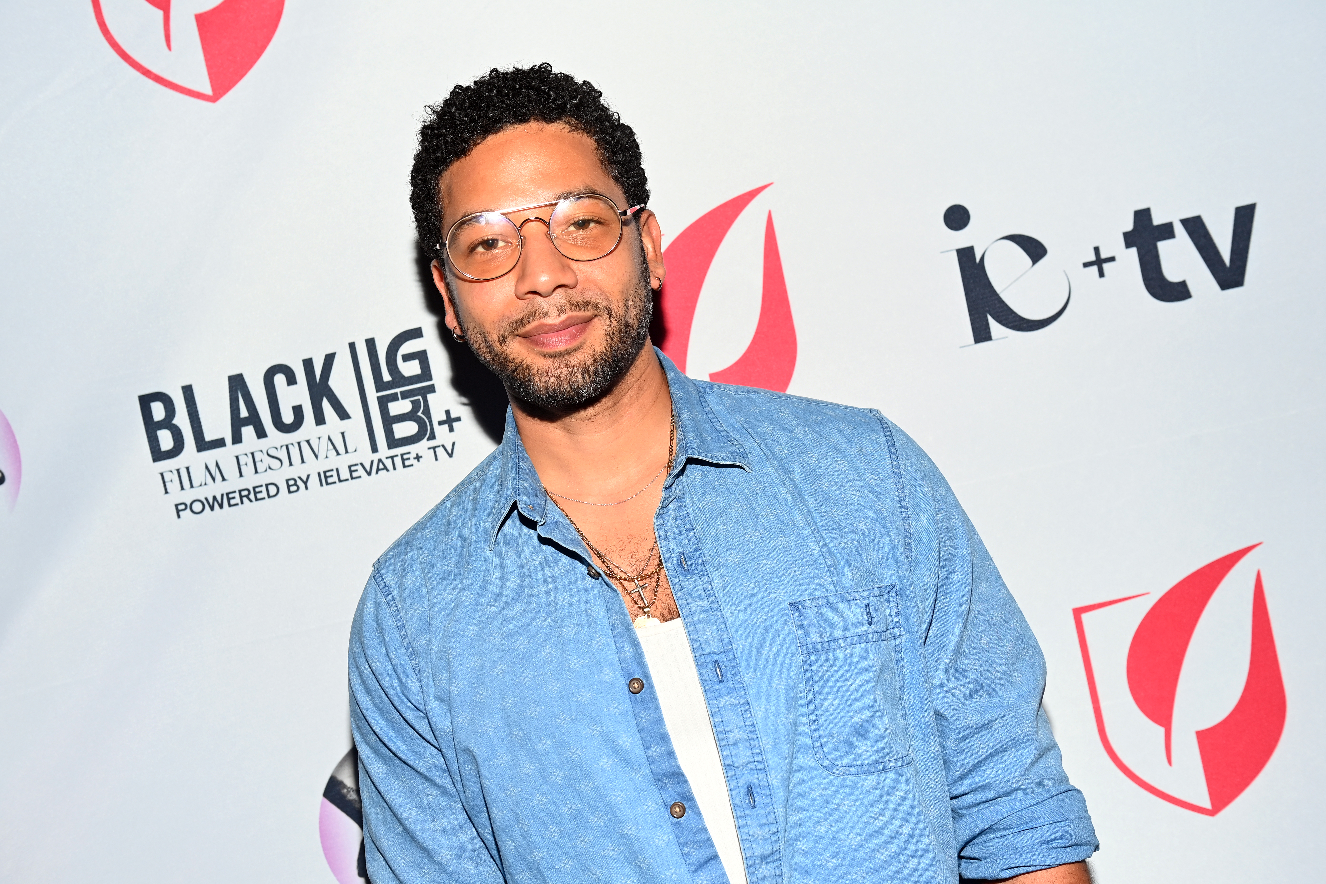 Jussie Smollett wearing a denim jacket over a white vest. He