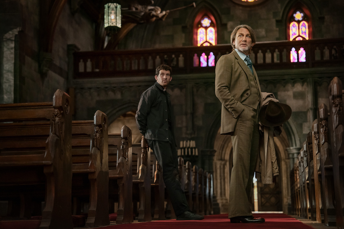 Wake Up Dead Man: A Knives Out Mystery still: Daniel Craig standing in a church to the right of frame with Josh O