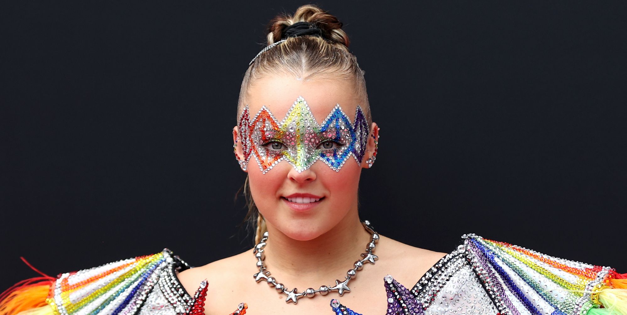 JoJo Siwa in rainbow make-up and outfit.