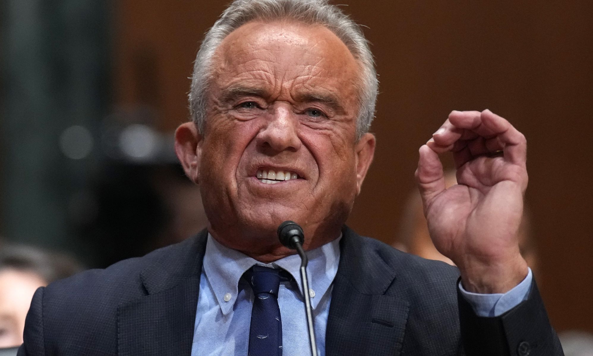 Robert F Kennedy Jr pictured speaking into a microphone with his hand in the air.