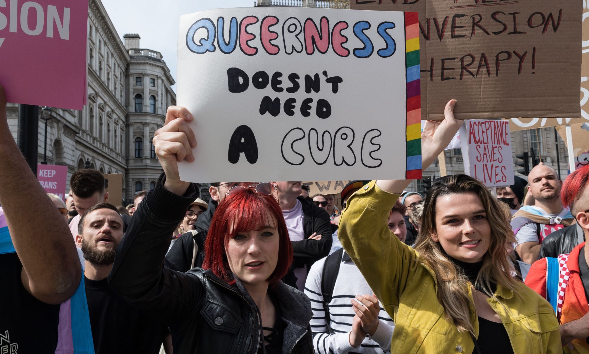 Protestors holding signs supporting a ban on conversion therapy.