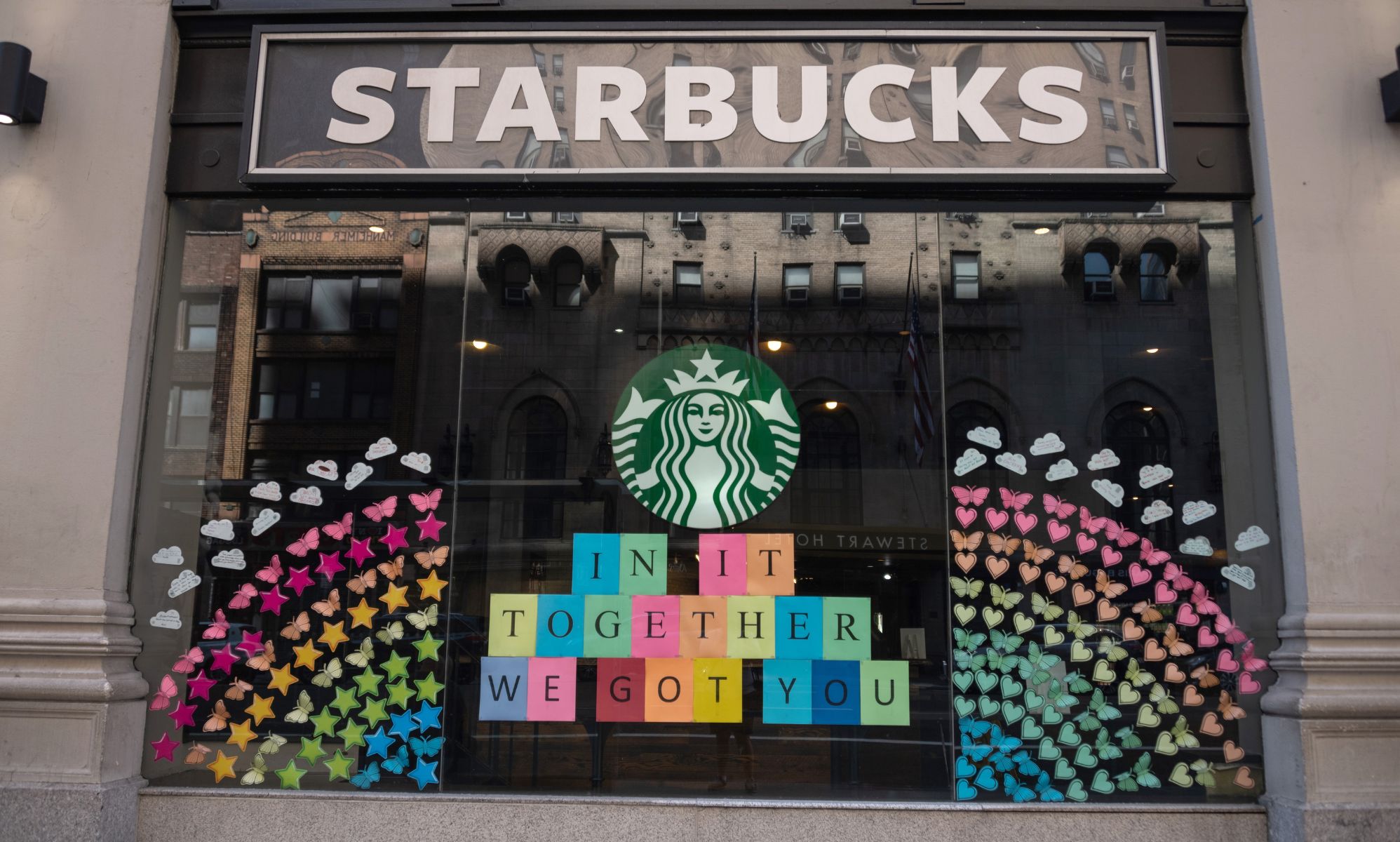 The front of a Starbucks branch with Pride art on the wall.