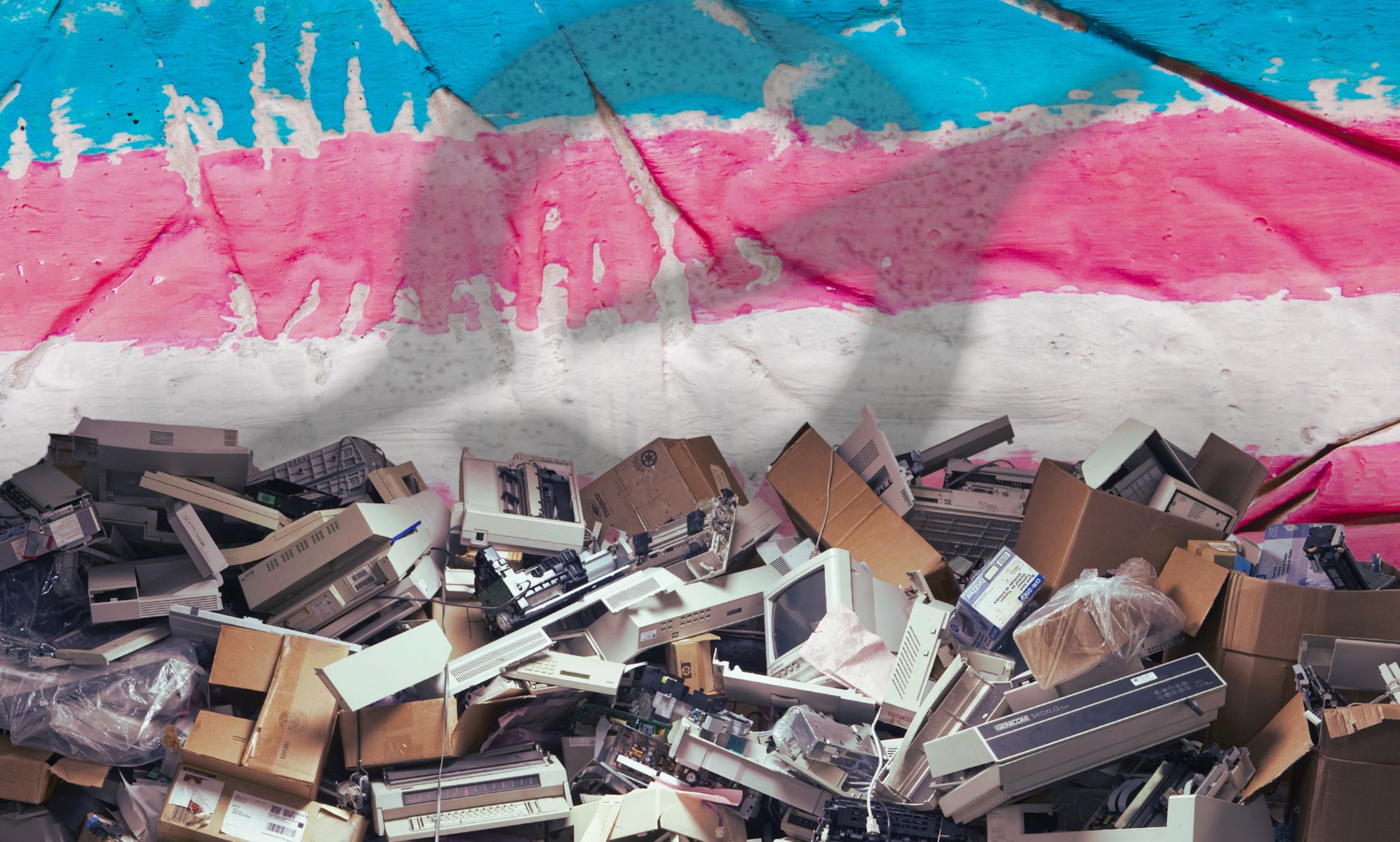 A pile of broken tech edited in front of a trans flag with the Grok logo superimposed over it.