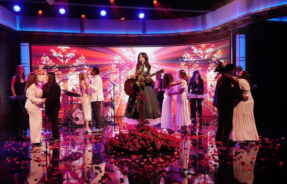 Lucy Dacus singing on Jimmy Kimmel Live! while four couples dance around her in wedding suits and dresses.