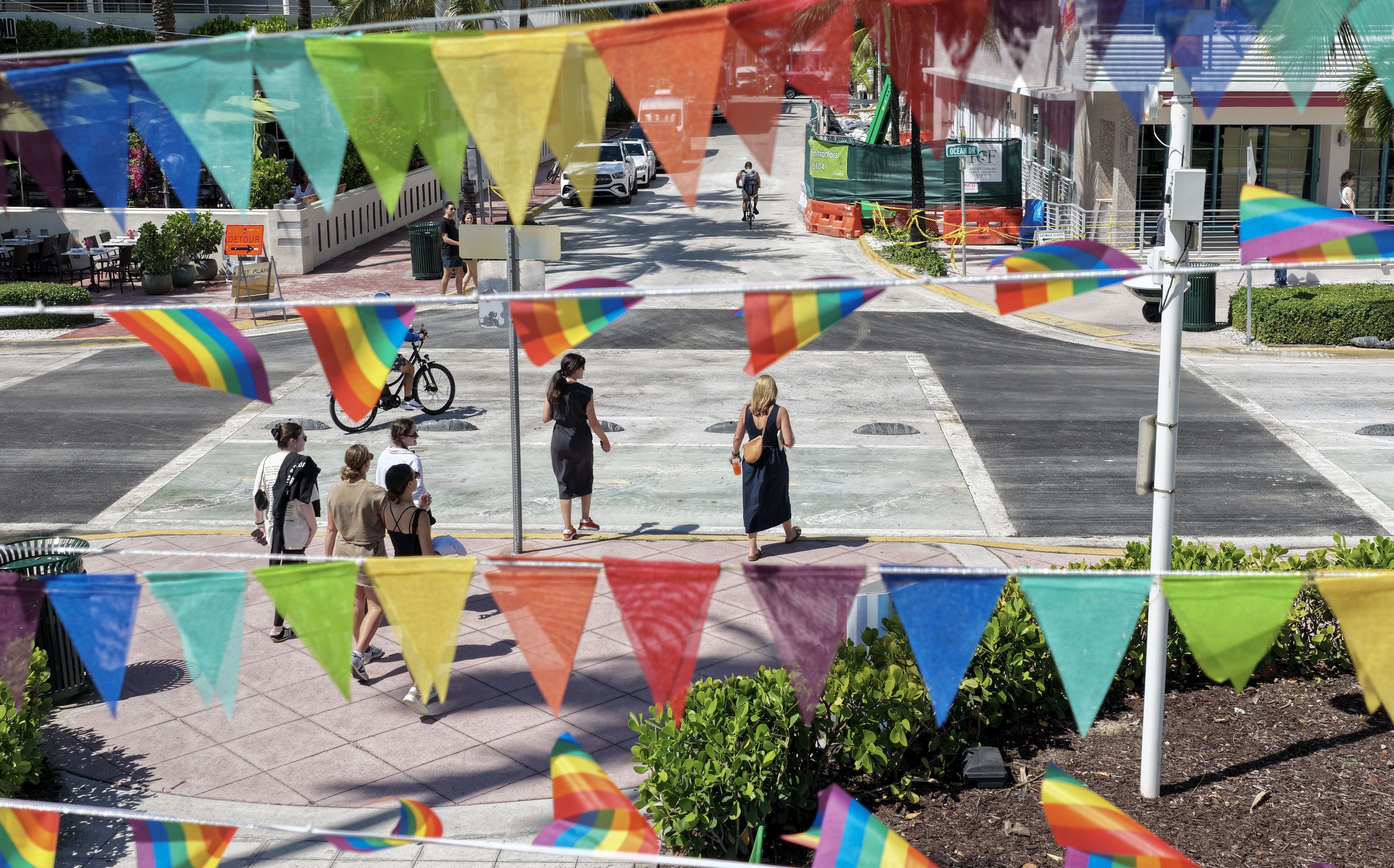 Pride flags fly near the intersection where the Florida Department of Transportation removed the LGBTQ+ rainbow crosswalk and replaced it with black pavement.