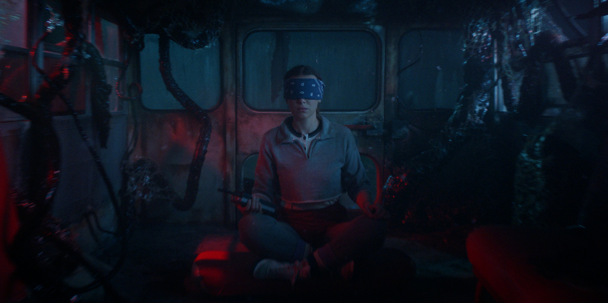 Millie Bobby Brown as Eleven in Stranger Things season 5, blindfolded in the back of a dark van.