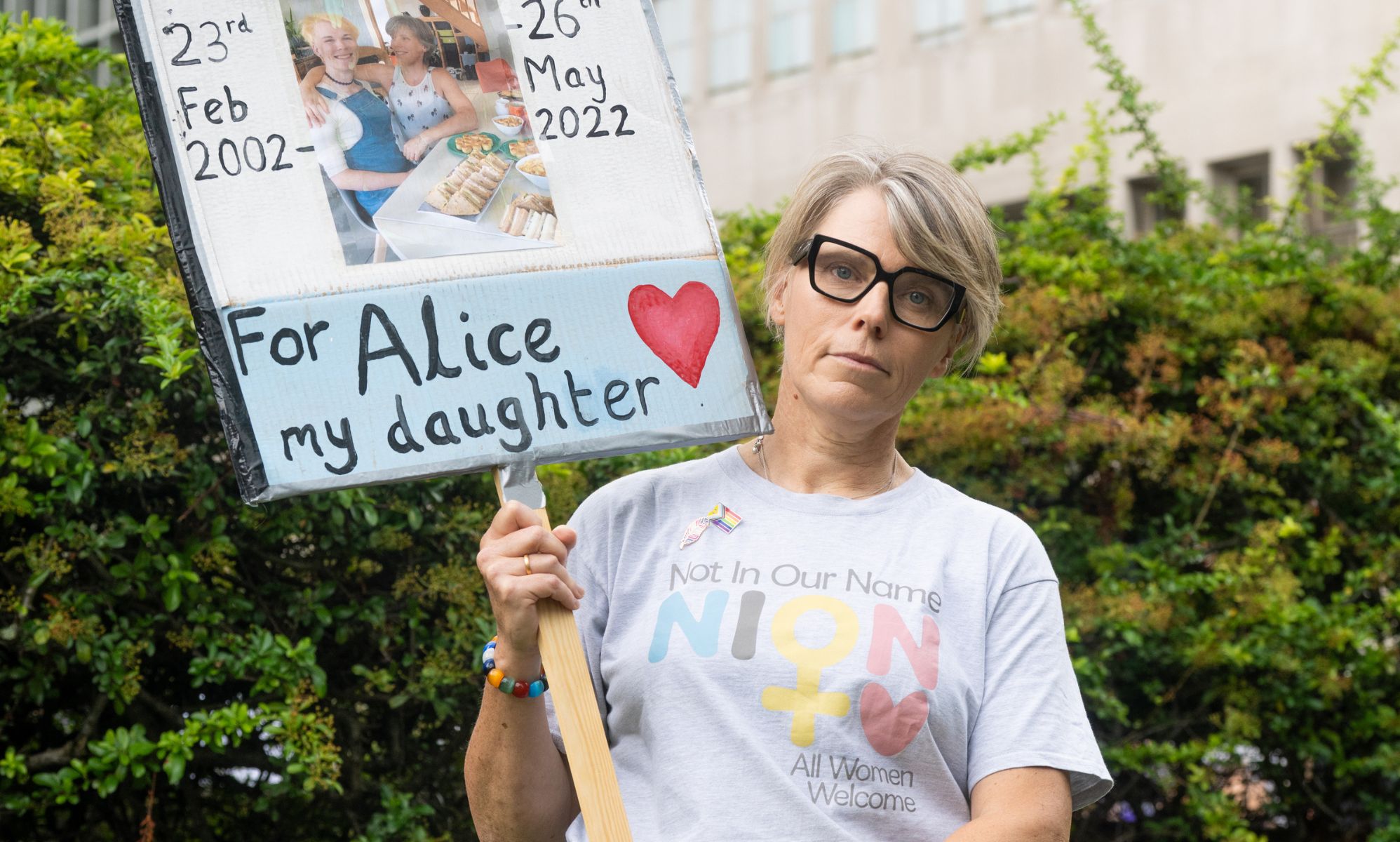 A woman holding a sign in the centre of a London field.