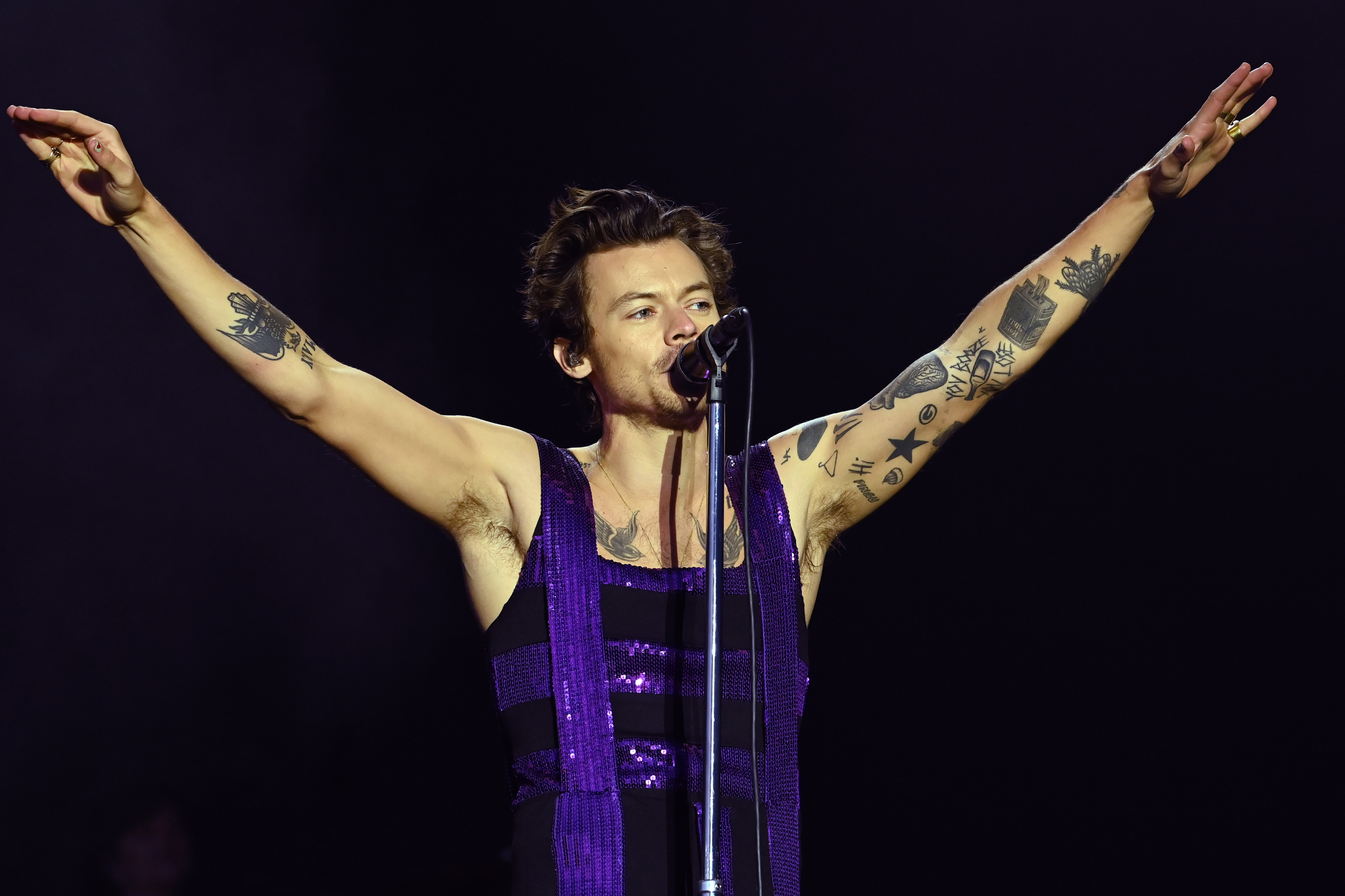 Harry Styles performing in a purple sequin jumpsuit