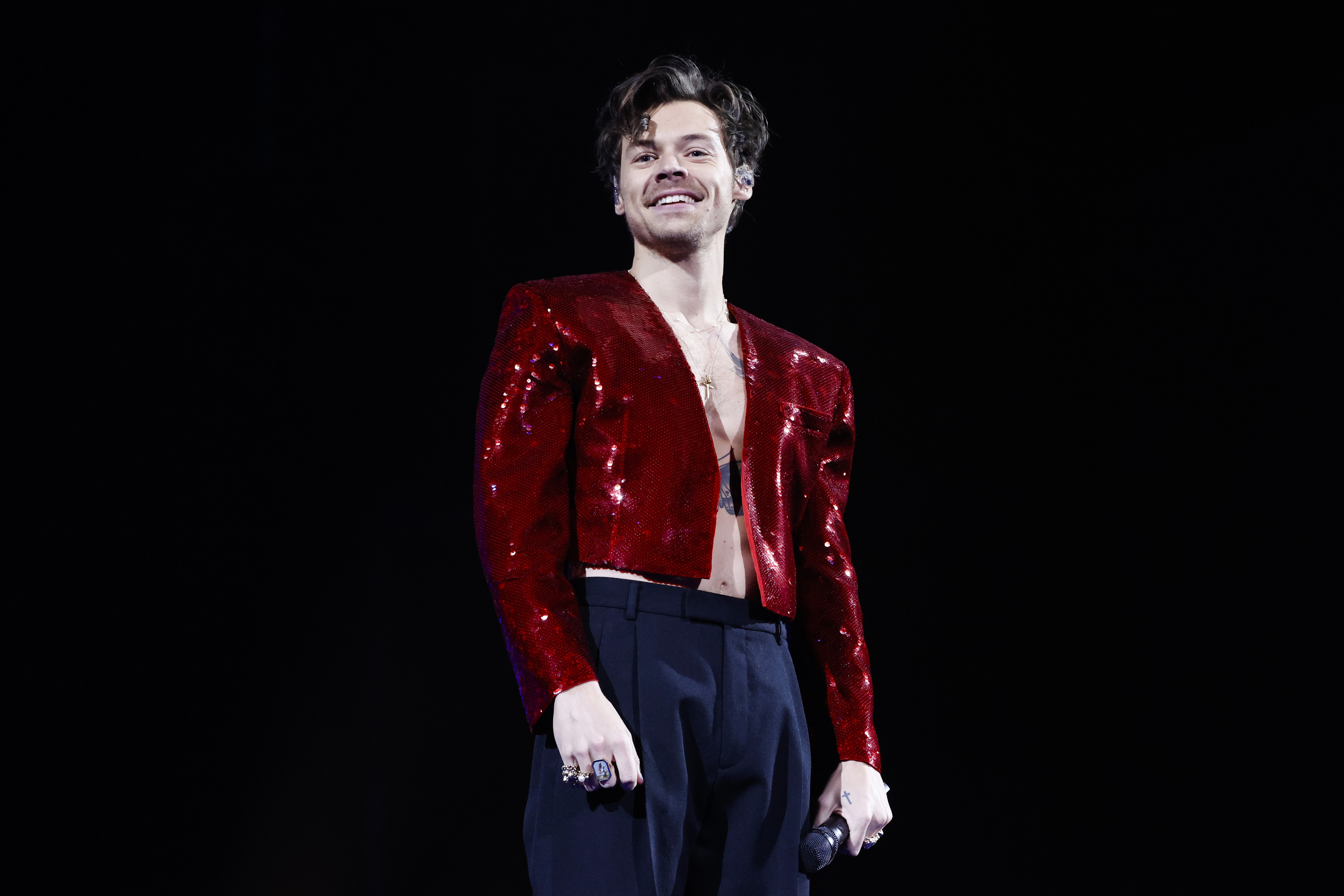 Harry Styles on tour in a shiny red jacket