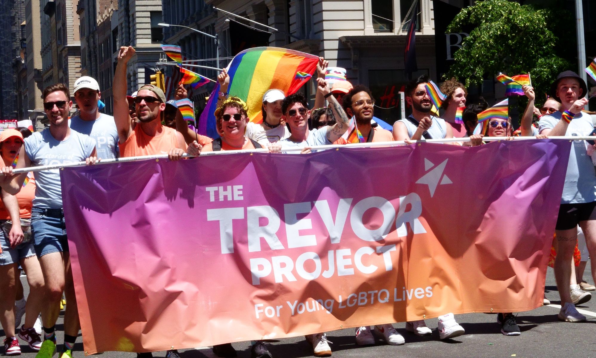 A crowd of people holding a banner for The Trevor Project during a Pride march.