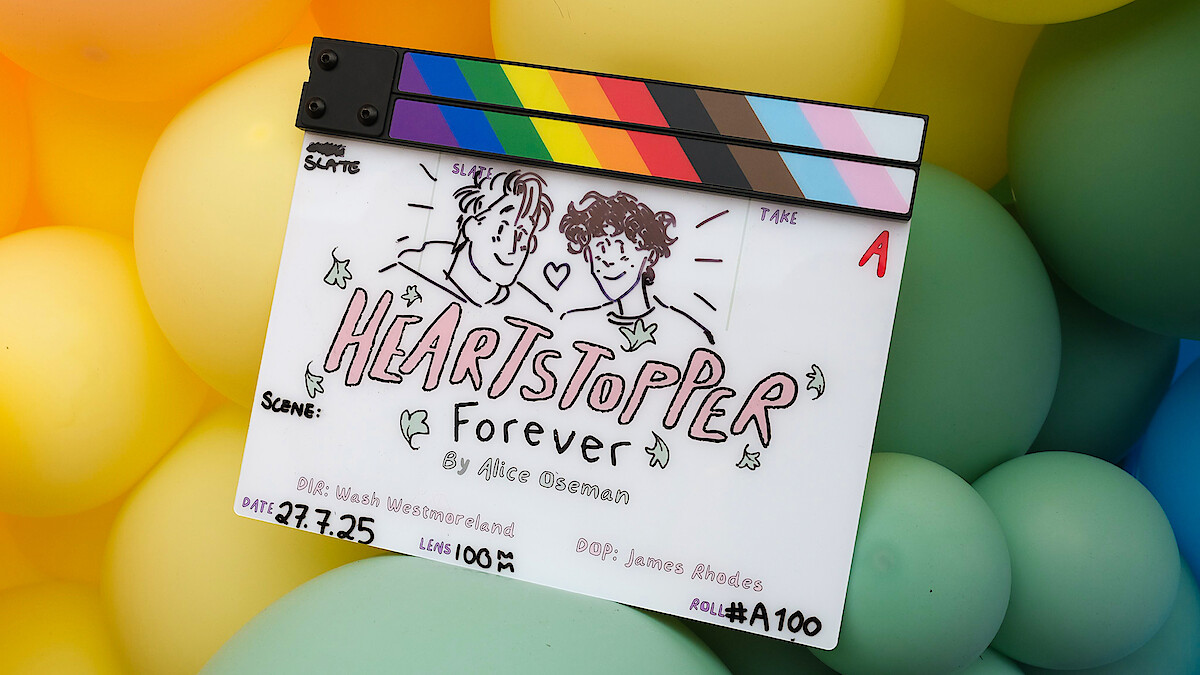 Film clapperboard of Heartstopper forever by alice oseman on top of rainbow balloons